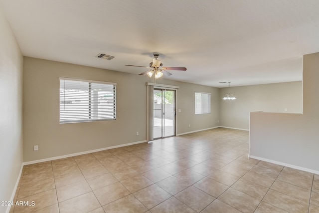 unfurnished room with ceiling fan with notable chandelier and light tile patterned floors