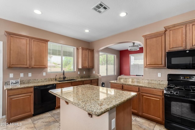 kitchen featuring visible vents, arched walkways, a center island, a sink, and black appliances