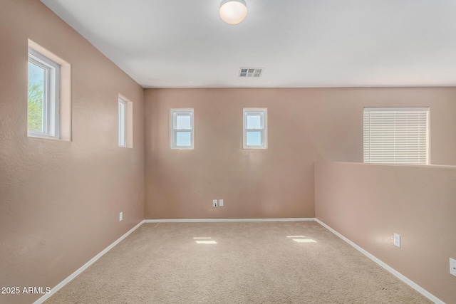 carpeted empty room featuring baseboards and visible vents