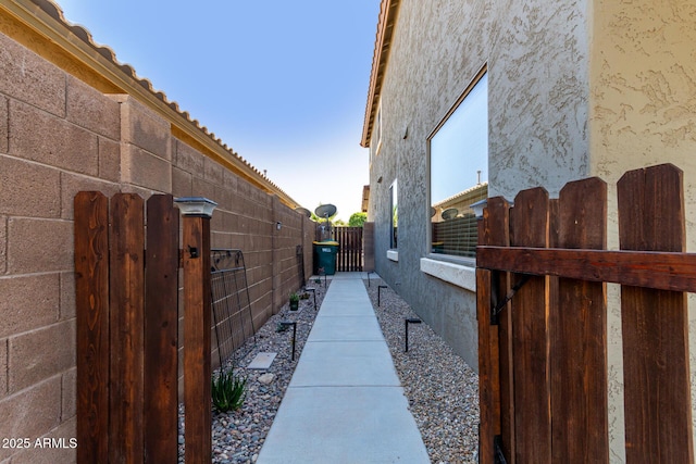 view of property exterior with fence, a gate, and stucco siding