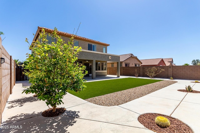 back of house featuring a lawn, a fenced backyard, a patio area, and stucco siding