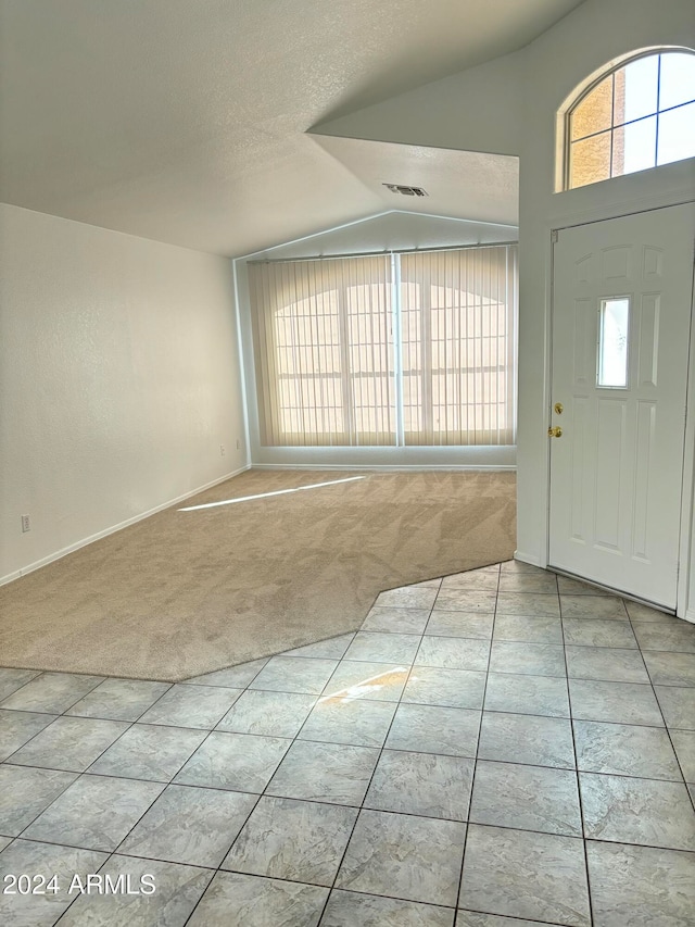 carpeted entrance foyer with lofted ceiling