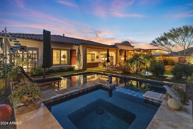 pool at dusk featuring an in ground hot tub and a patio area