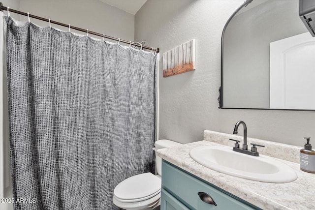 full bath featuring a textured wall, a shower with shower curtain, vanity, and toilet