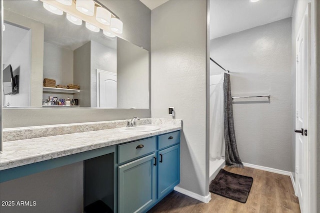 bathroom featuring baseboards, a shower stall, vanity, and wood finished floors