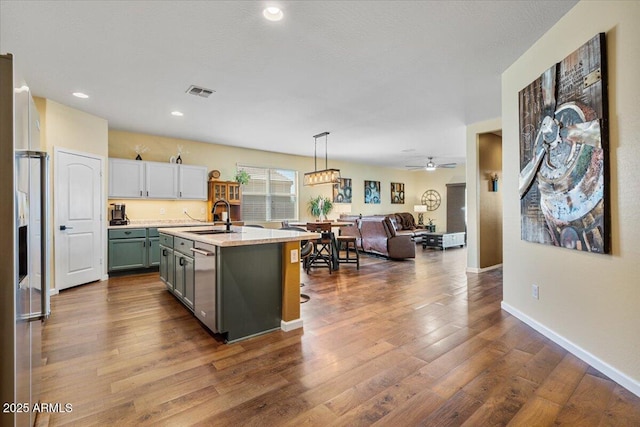 kitchen featuring visible vents, a sink, open floor plan, dark wood-style flooring, and stainless steel dishwasher