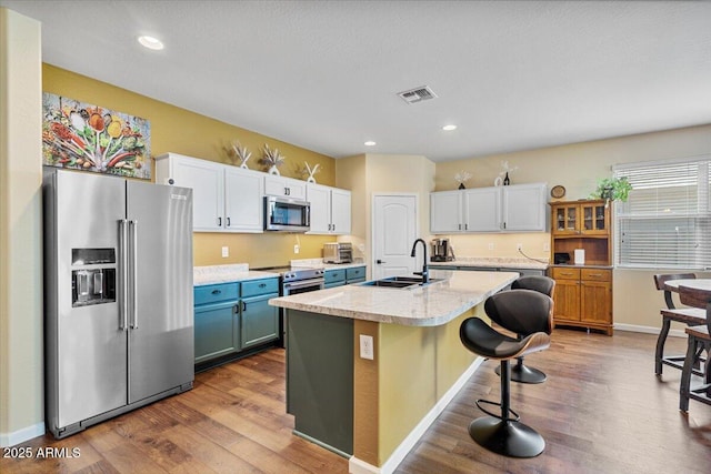 kitchen featuring light countertops, visible vents, stainless steel appliances, a sink, and wood finished floors