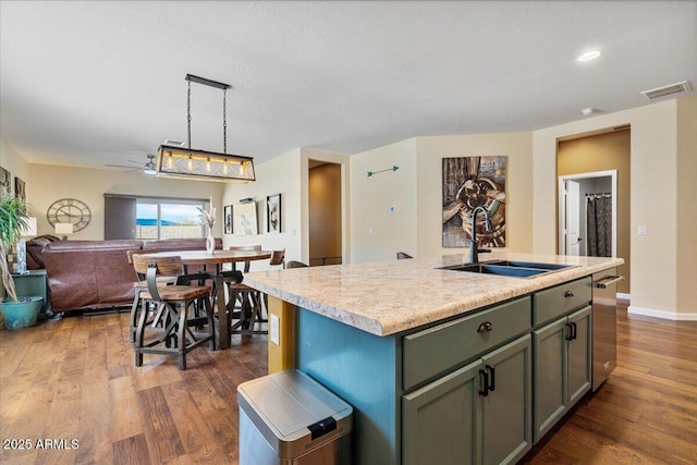 kitchen featuring open floor plan, dark wood-style floors, light countertops, visible vents, and a sink