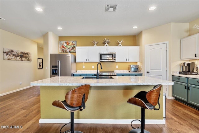kitchen featuring a sink, visible vents, a kitchen bar, and stainless steel appliances