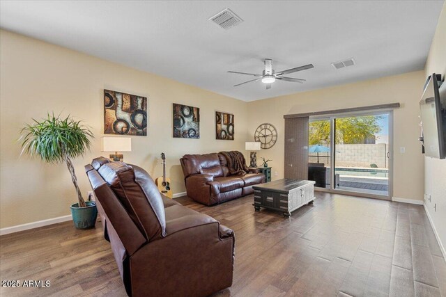living room featuring visible vents, baseboards, a ceiling fan, and wood finished floors