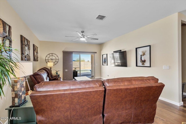 living area featuring wood finished floors, baseboards, a ceiling fan, and visible vents