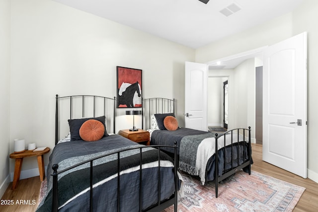 bedroom with light wood-style floors, visible vents, and baseboards