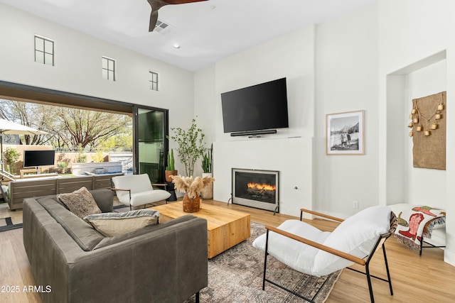 living room featuring wood finished floors, visible vents, recessed lighting, ceiling fan, and a lit fireplace