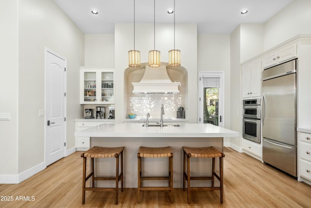 kitchen with stainless steel appliances, a kitchen bar, light countertops, and a sink