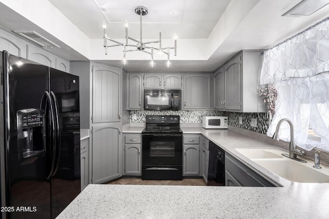 kitchen featuring black appliances, hanging light fixtures, light countertops, and gray cabinetry