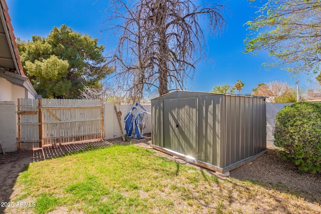 view of yard with a storage shed, a fenced backyard, and an outbuilding