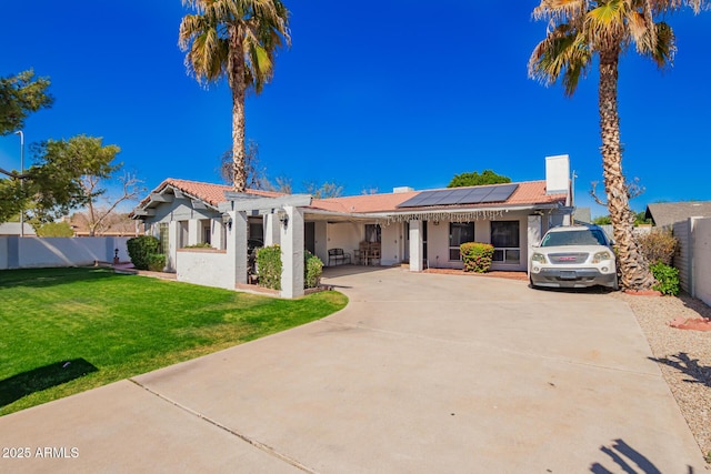 view of front of home featuring roof mounted solar panels, driveway, a front lawn, and fence