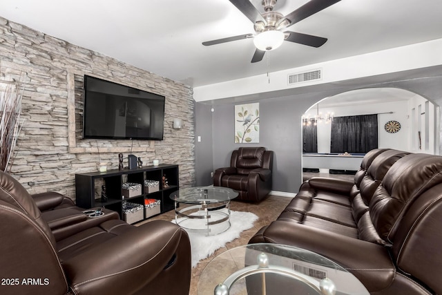 living area with a ceiling fan, arched walkways, visible vents, and baseboards