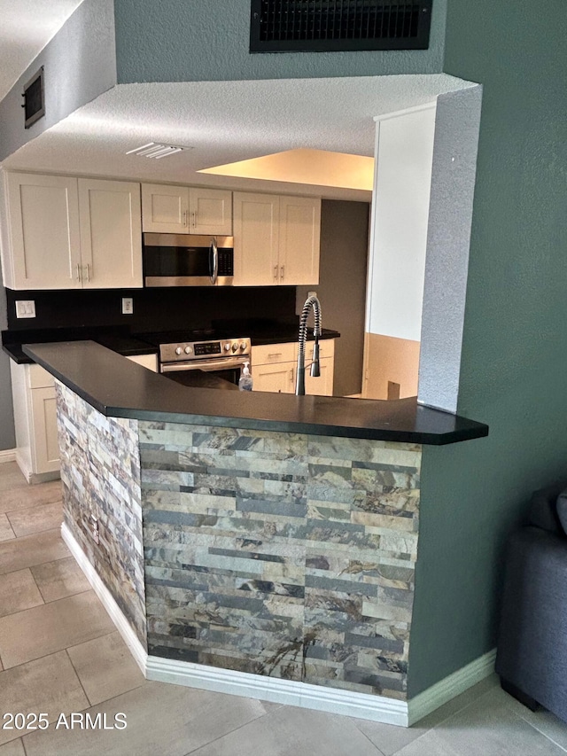 bar featuring white cabinets, sink, and stainless steel appliances