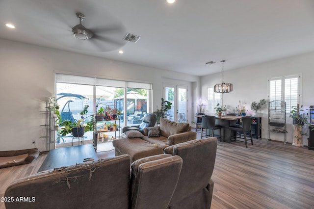 living room featuring hardwood / wood-style flooring, plenty of natural light, ceiling fan with notable chandelier, and french doors