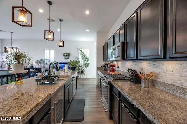 kitchen featuring stainless steel appliances, dark brown cabinetry, light stone counters, and decorative light fixtures