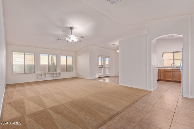 unfurnished living room featuring french doors, light carpet, a wealth of natural light, and ceiling fan