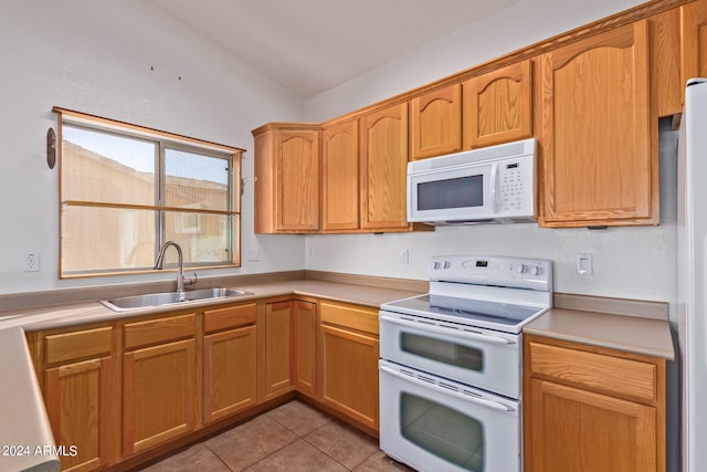 kitchen featuring lofted ceiling, sink, light tile patterned flooring, and white appliances