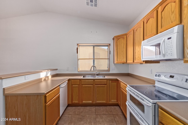 kitchen with dark tile patterned floors, sink, vaulted ceiling, and white appliances