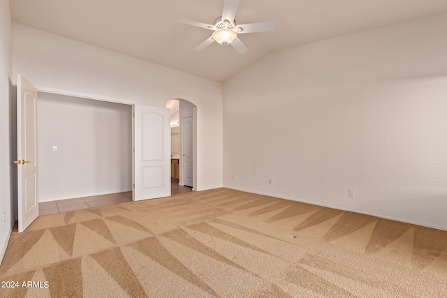 unfurnished bedroom with vaulted ceiling, light colored carpet, a closet, and ceiling fan