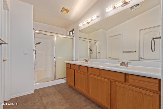 bathroom featuring a shower with door, lofted ceiling, vanity, and tile patterned flooring