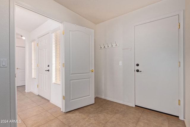 foyer entrance featuring light tile patterned floors and vaulted ceiling