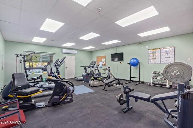 workout area featuring an AC wall unit and a drop ceiling