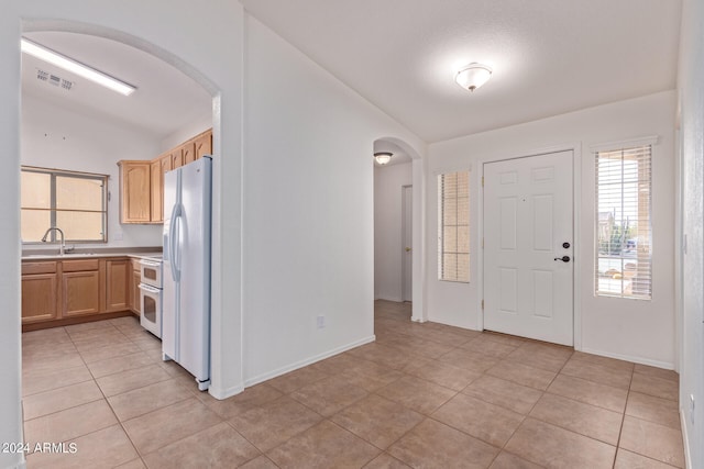 tiled foyer featuring lofted ceiling, sink, and plenty of natural light