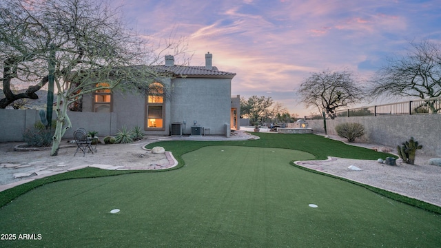 yard at dusk featuring cooling unit, a patio, and fence