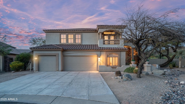 mediterranean / spanish-style house with a balcony, driveway, stucco siding, a garage, and a tiled roof