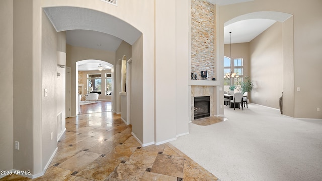 corridor with arched walkways, a high ceiling, carpet floors, baseboards, and a chandelier