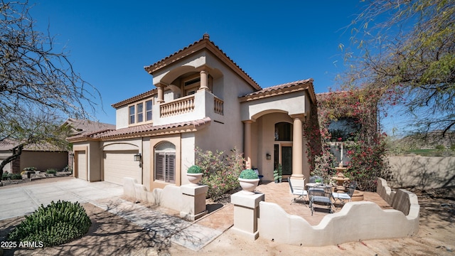 mediterranean / spanish house featuring a tile roof, a balcony, driveway, and stucco siding