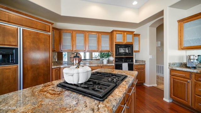 kitchen with visible vents, brown cabinetry, arched walkways, black appliances, and dark wood-style flooring