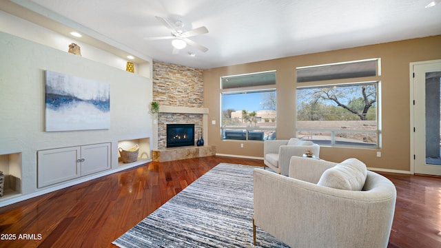 living area with a ceiling fan, wood finished floors, baseboards, and a fireplace