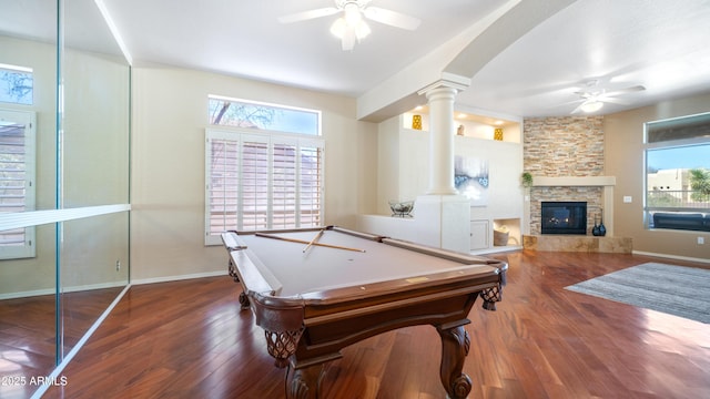 game room with ceiling fan, decorative columns, a stone fireplace, wood finished floors, and billiards