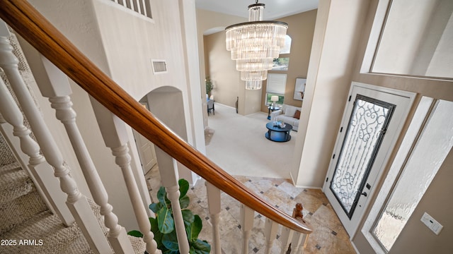 foyer entrance with visible vents, an inviting chandelier, stairs, a towering ceiling, and carpet flooring