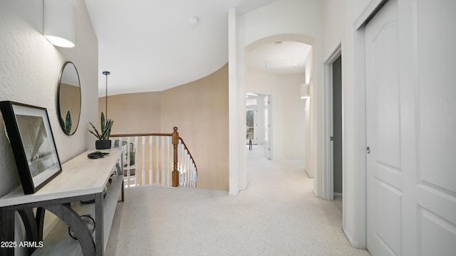 corridor featuring an upstairs landing and arched walkways