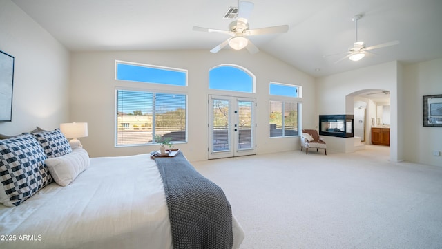 bedroom with a ceiling fan, access to outside, french doors, arched walkways, and light colored carpet