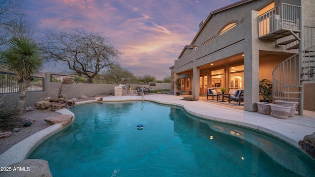 pool at dusk with a patio area, a fenced in pool, and a fenced backyard