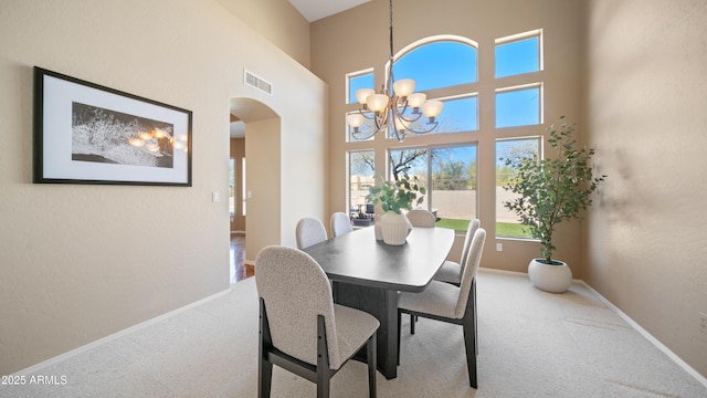 carpeted dining space featuring an inviting chandelier, visible vents, arched walkways, and baseboards