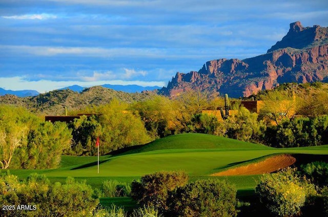 surrounding community with view of golf course, a lawn, and a mountain view