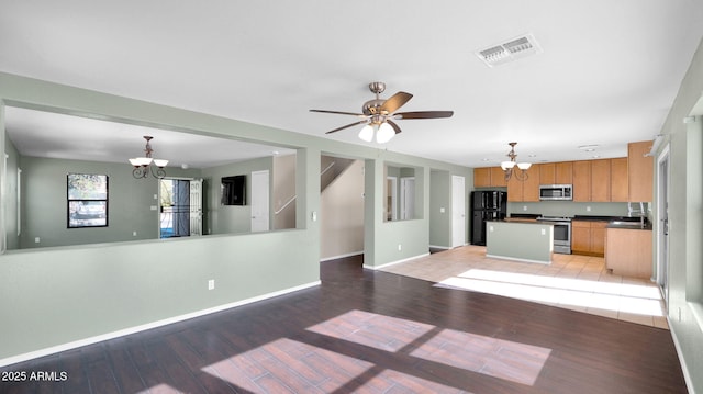 kitchen featuring pendant lighting, a center island, ceiling fan with notable chandelier, light wood-type flooring, and appliances with stainless steel finishes