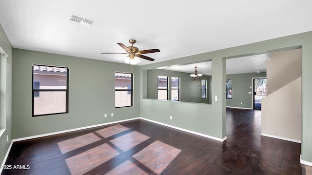 empty room with ceiling fan with notable chandelier and dark hardwood / wood-style floors