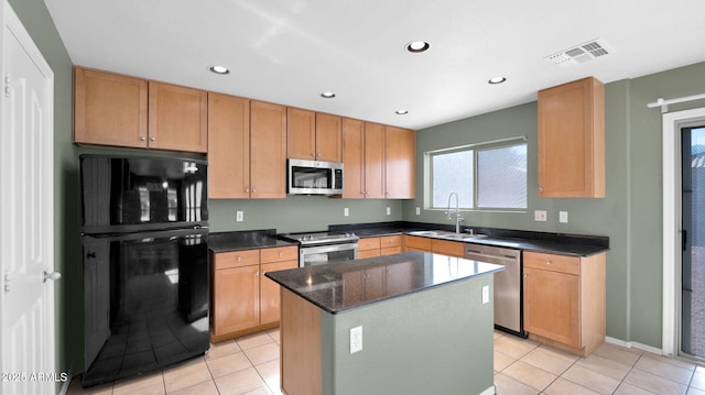 kitchen with a kitchen island, light tile patterned floors, sink, and appliances with stainless steel finishes