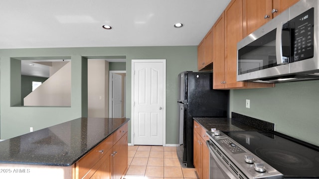 kitchen with dark stone countertops, light tile patterned flooring, and appliances with stainless steel finishes